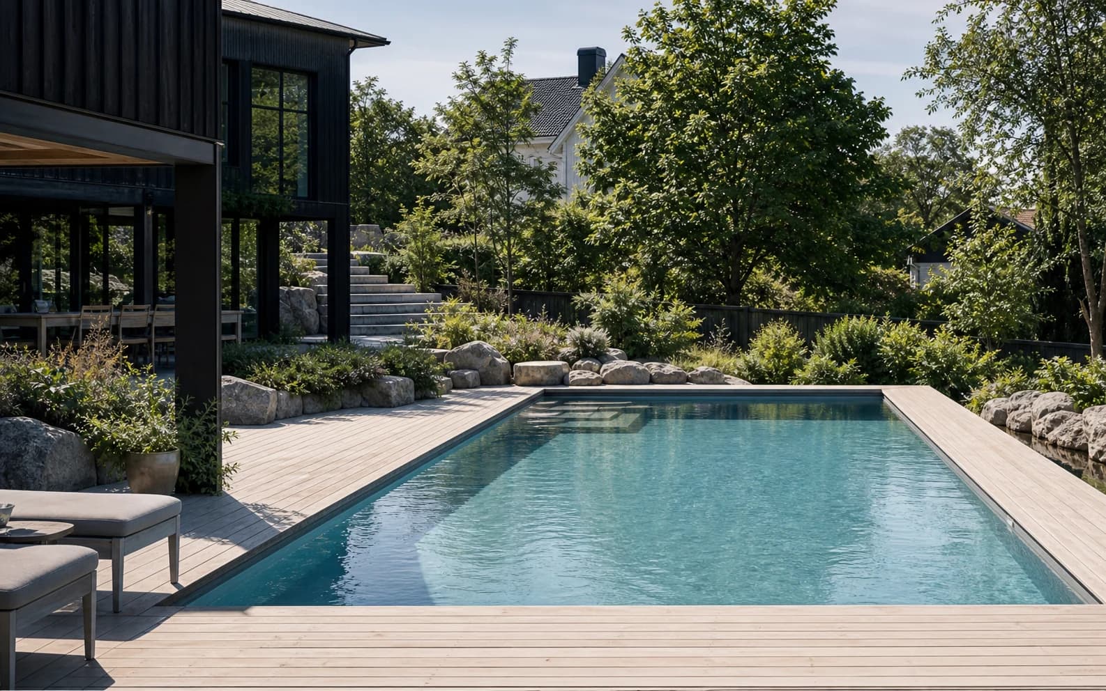 Modern villapool med trädäck, grönska och tydlig utemiljö